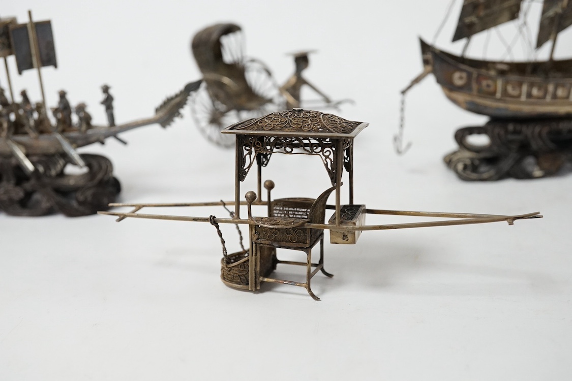 A Chinese white metal miniature model of a junk, length 11.2cm, on a wooden stand, a similar late 19th/early 20th century miniature filigree sedan chair and rickshaw by Kwan Wo and a Chinese white metal model of a boat w